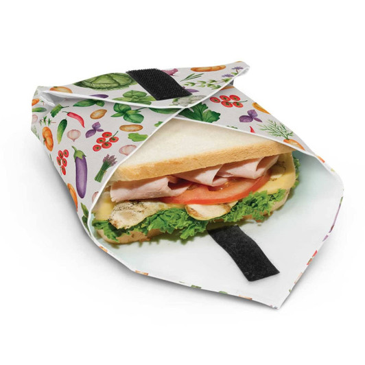 A reusable food wrap featuring a colourful fruit and vegetable pattern, holding a sandwich inside.