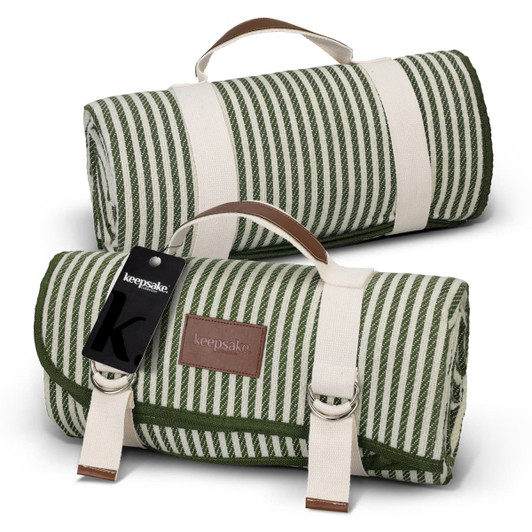 A green and white striped picnic blanket, rolled up with handles, featuring a leather accent and a branding tag.