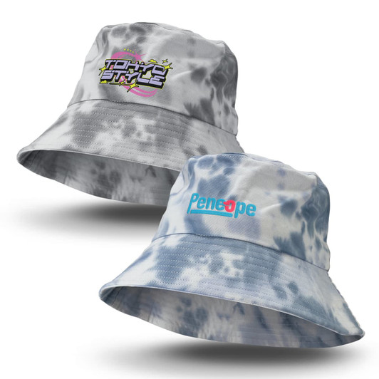 A grey and blue tie dye bucket hat featuring a logo on one side and text on the other.