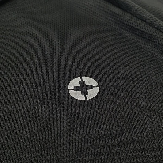 A close-up of a black polo shirt featuring a logo on the chest area.