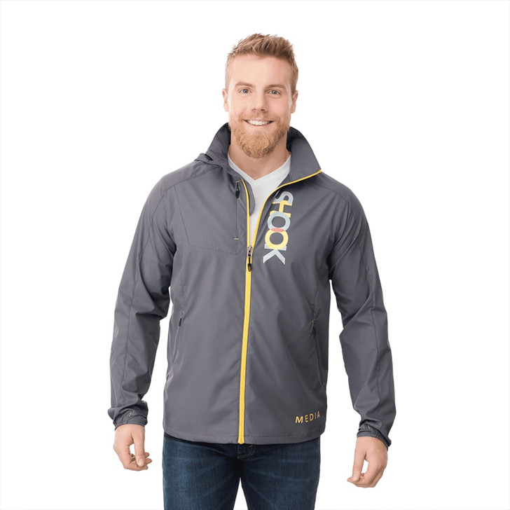 A man wearing a grey lightweight jacket with yellow accents and a logo on the front.