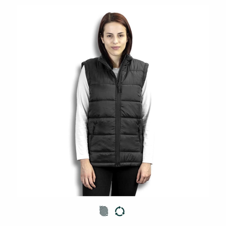 A woman stands wearing a black puffer vest over a white long-sleeve top. The vest features a zip front and has a logo.