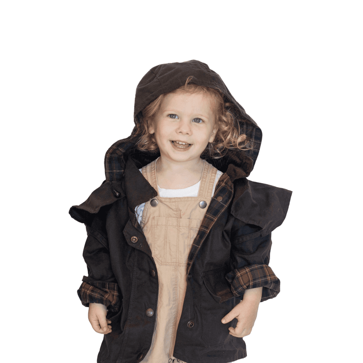 A child wearing a brown rain jacket with a hood and plaid lining, smiling while standing against a white background.