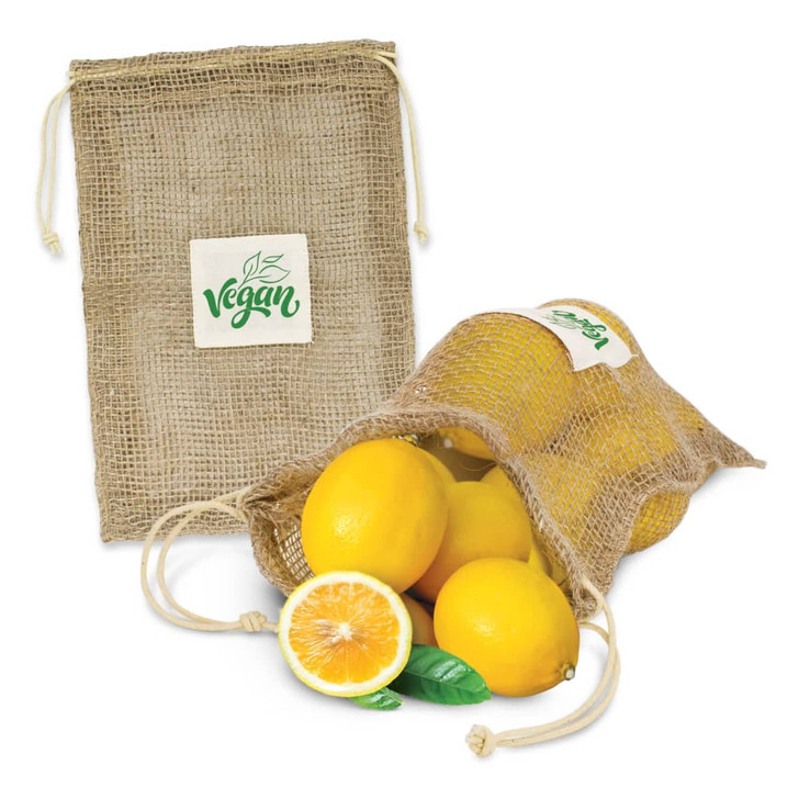 A jute net produce bag in natural colour, filled with lemons, alongside a lemon half and leaf. The bag has a logo.