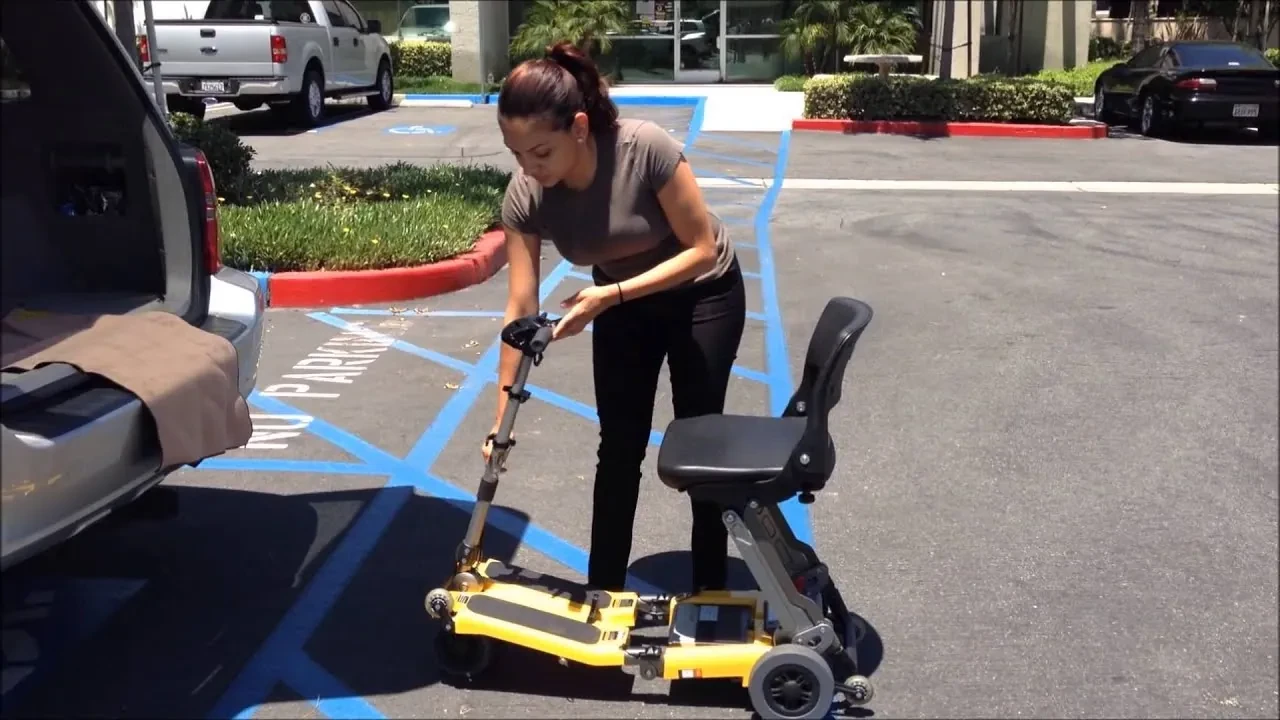 A woman beside an open SUV tailgate preparing a folding Luggie scooter to load into the car