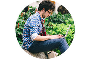 Man working on laptop next to bushes