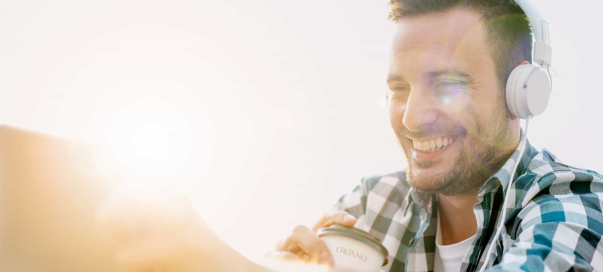Man with headphones on drinking from Organo cup.