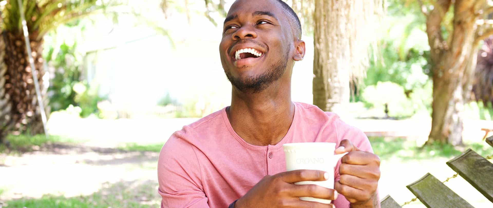 Man in red shirt sitting in forest holding an Organo cup.