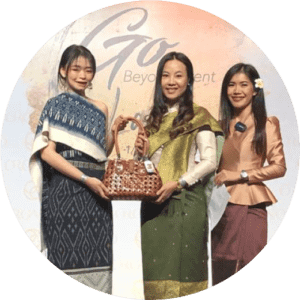 Three women holding bag being auctioned.