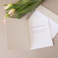 Open folded Mother’s Day card displaying heartfelt message for grandmother, shown with envelope and pink tulips on neutral surface.