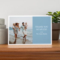 Folded thank you card featuring family beach photo and message text, displayed on wooden surface with modern home decor.