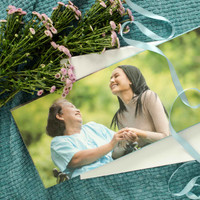 Layflat photo book featuring a mother and daughter holding hands and smiling outdoors, styled with flowers and ribbon.