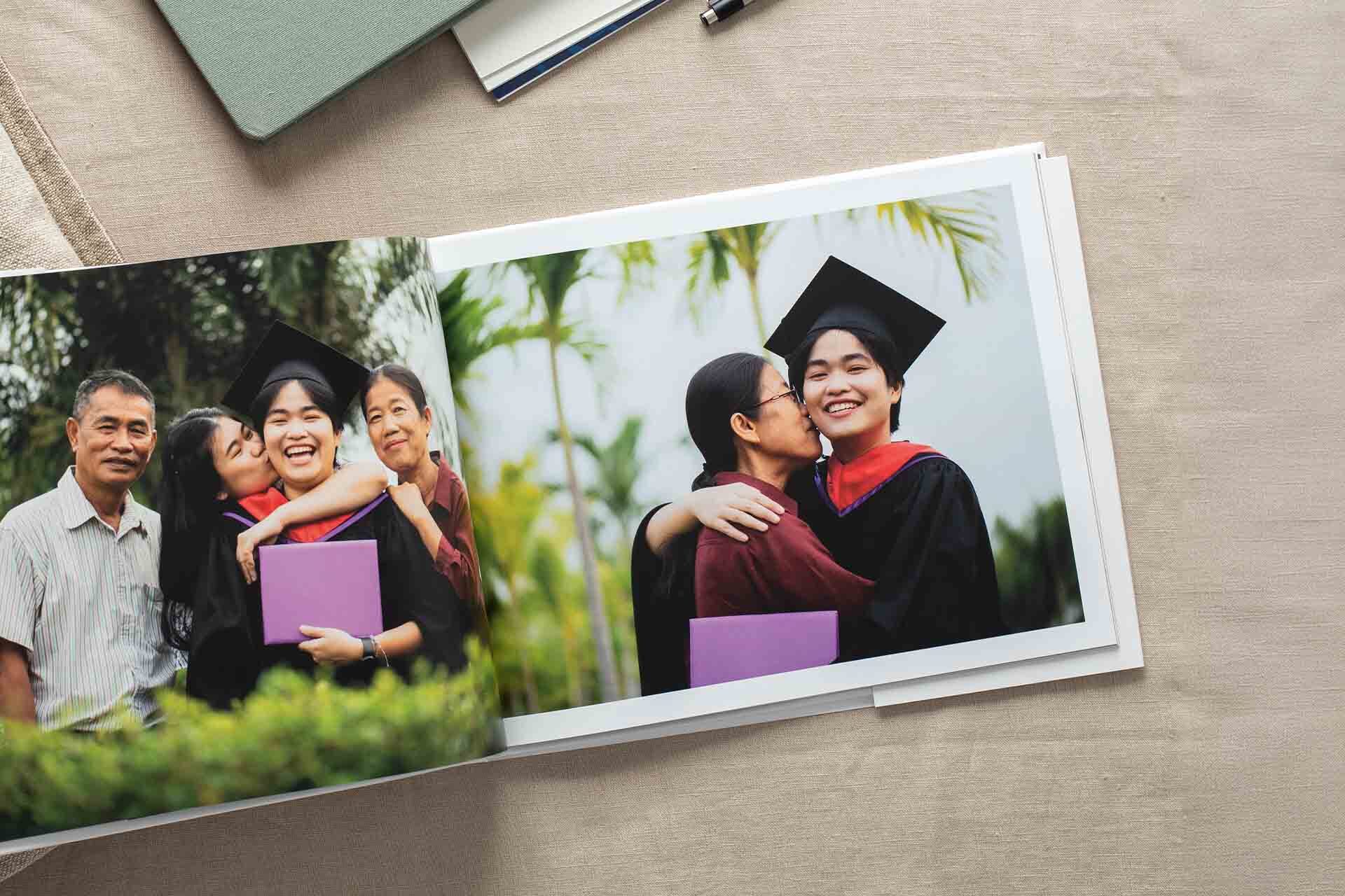 Open hardcover photo book featuring joyful graduation moments shared with family.