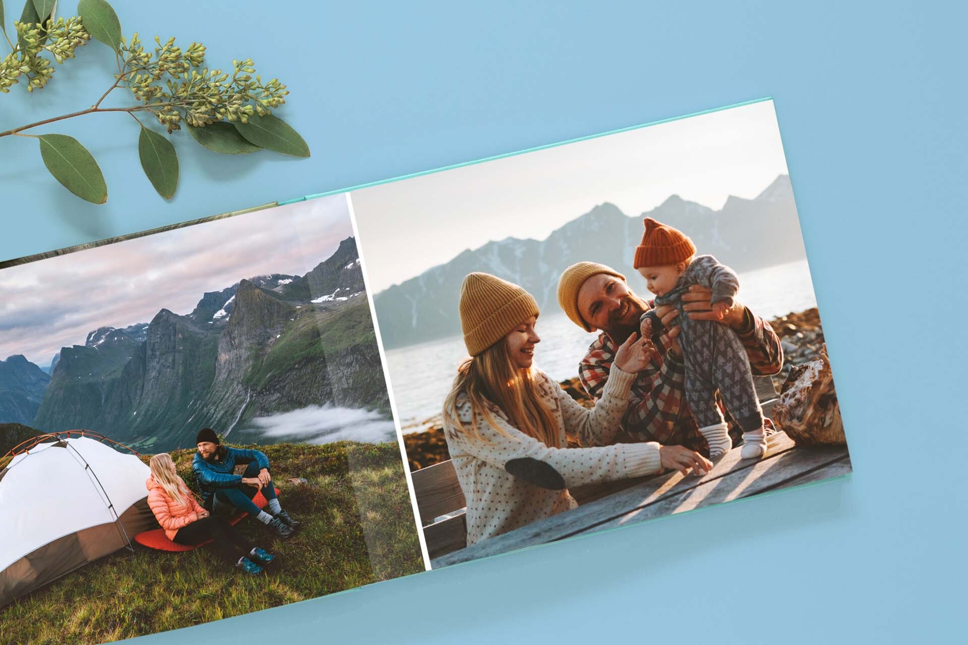 Layflat photo book spread with panoramic mountain camping photo on left and family portrait on right, displayed on blue background.