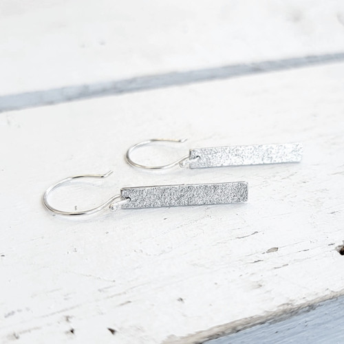 Sterling silver bars imprinted with sand gathered from the shores of idyllic Prince Edward Island (PEI), and tumbled to a glittery finish. Keep the beach with you all year round!
Each bar is 25mm x 5mm, and is finished with sterling silver french earwires. Sterling silver bars imprinted with sand gathered from the shores of idyllic Prince Edward Island (PEI), and tumbled to a glittery finish. Keep the beach with you all year round!
Each bar is 25mm x 5mm, and is finished with sterling silver french earwires.