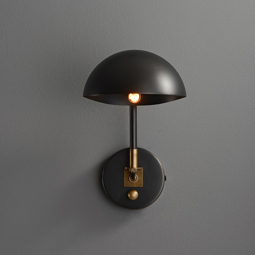 Front view of an illuminated Zack Dome Wall Sconce with Switch wall light, showing the dome-shaped shade, adjustable arm, gold details, and the switch on the round base.