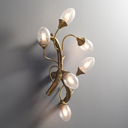 Side view of an illuminated Tree Branch Wall Sconce wall light, with its metal frame resembling a tree branch, holding five lit seeded glass shades.