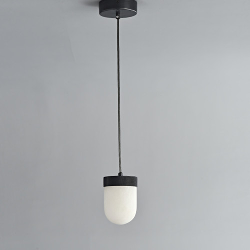 An unlit Erica Alabaster Pendant hanging from the ceiling, featuring a metal canopy with bronze finish and a capsule-shaped natural alabaster shade.