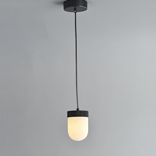 An illuminated Erica Alabaster Pendant hanging from the ceiling, featuring a metal canopy with bronze finish and a capsule-shaped glowing alabaster shade. An illuminated Erica Alabaster Pendant hanging from the ceiling, featuring a metal canopy with bronze finish and a capsule-shaped glowing alabaster shade.