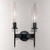 Front view of an unlit Aicken Double Sconce Bronze double wall light, emphasizing the clear cylindrical glass shades with visible bulbs inside and the metal base and arms with a brushed bronze finish.