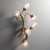 Side view of an illuminated Tree Branch Wall Sconce wall light, with its metal frame resembling a tree branch, holding five lit seeded glass shades.