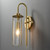 Side view of an illuminated Crackle Glass Wall Sconce wall light, showing the curved metal arm supporting the crackle-textured glass shade, with the light source visible inside.