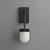 An unlit Erica Alabaster Wall Sconce Bronze, mounted on a wall, viewed from the front showing the metal backplate with bronze finish and capsule-shaped natural alabaster shade.