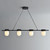 An illuminated Erica Alabaster Linear Pendant 4 Lights, viewed from the front, featuring four capsule-shaped glowing alabaster shades neatly arranged along a black metal bar.