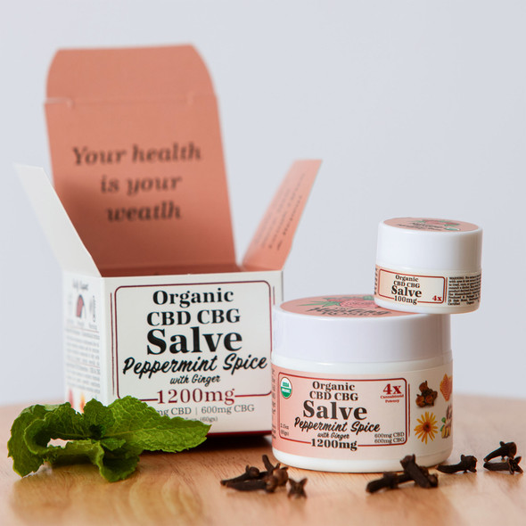 The Healing Rose Peppermint Spice Organic CBD CBG Salve in large and small jars beside clove buds and fresh peppermint leaves