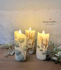 Belles and Whistles Cotton and Eucalyptus - Rub On Furniture Transfer, Best Transfers for Furniture 
This picture shows 3 , lit candles that all have a cotton and eucalyptus transfer on them.  They rest on a ashy, wood table.  There are real eucalyptus branches wrapped around the bases of the candles and are all infront of a textured, white, stucco wall.
