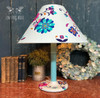 Belles and Whistles Latin Floral - Rub On Furniture Transfer, Best Transfers for Furniture Makeovers!
A white lamp with the stand a gradient blue to white. On the base and the lampshade are covered in Latin Floral Transfer . Staged on a a brown table with books lined up next to a plant in a tin can along with a leaf wreath.