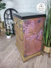Belles and Whistles Cherry Blossom - Rub On Furniture Transfer, Best Transfers for Furniture!
A brown Bedside dresser with a black top and the side panel using  Cherry Blossom - Transfer, Staged along with potted plants along the piece.