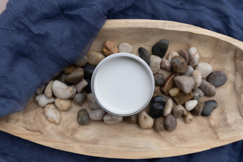 Overhead shot of an open jar of Glacier. Staged in a wooden bowl with rocks on a navy blue sheet.