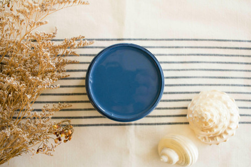 Cape Current Silk All-In-One paint is perfect for painting kitchen cabinets, bathroom cabinets and painting furniture.
Opened container of Cape Current Silk All-In-One Mineral Paint® staged with seashells and dried flowers on top of a white and blue striped cloth.