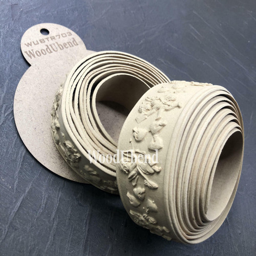 WoodUBend Trim #TR703 (Set of 2) is the perfect mouldable embellishment for any project!  two rolled up strips of WoodUBend sitting on a circular piece of brown paper that has WoodUbend WUBTR703 printed on it.  All are on top of a black table.