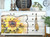A beautifully refurbished painted dresser with a vibrant Sunny Daze A1 Rice Decoupage Paper illustration across its drawers, adorned by bronze knobs, gold tassels, and flanked by decorative home accessories.