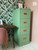 Dixie Belle Paint Mint Julep Chalk Mineral Paint is the perfect paint for any DIY project!
Mint green Chalk painted file cabinet. Staged in front of a tropical leaves wallpaper with a pink chair and wood desk with computer next to it.