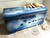 WoodUBend Ring Applique #1520 (set of 2) A trunk painted in white, blue, and black and blended as the night sky featuring the moulds and birds on a line in the front and on top. This trunk is styled with a blanket and book on the right side.