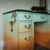 Belles and Whistles Steampunk - Rub On Furniture Transfer, Best Transfers for Furniture. 
Office desk with a light blue and orange gradient effect with the Steampunk - Transfer shown on drawers and side piece with . Staged with a black vintage typewriter on top.