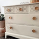 Belles and Whistles Buffalo Check - Stencil provides an extra decorative touch to any project!
A cream colored dresser with the first row of 3 drawers using the Buffalo Check - Stencil with a gray tone and wood hardware.