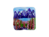 Bring the beautiful scenery of this Grace Lampwork Bead into your designs. This focal bead has a square shape and the front features a puffed dimension. The front features a scene of the Rocky Mountains behind a beautiful lake. The back is plain and flat, so it will lay nicely in designs. String this bead onto a head pin to turn it into a pendant or showcase it at the center of a bead embroidery project. This item is handmade, so appearances may vary. Dimensions: 26 x 26mm, Hole Size: 2.5mm