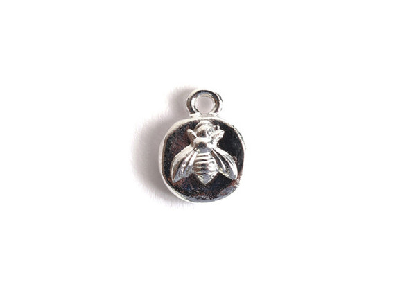 Bring some buzz to your designs with this itsy organic bee charm from Nunn Design. This small charm has a circular shape and features a raised design of a bee.  The back is plain. This charm has bright silver shine.