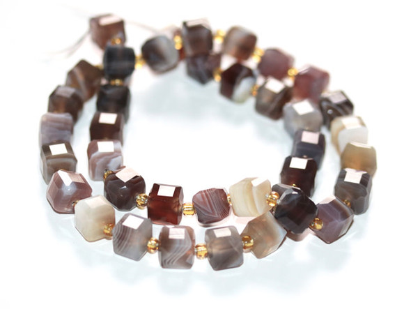 Bring gemstone style to your designs with these Dakota Stones 7 x 10mm table cut cube beads. These beads feature a cube shape with table facets. Botswana Agate was formed nearly 187 million years ago by lava flowing in waves from long faults in the earth. As the lava rolled across landscape, it deposited layer upon layer of Quartz silicate, creating the defined parallel banding and patterns that are now the prized characteristics of Botswana Agate. It is usually found in white on hues of brown, gray, pink, tan, apricot, and purplish red colors.Because gemstones are natural materials, appearances may vary from bead to bead.