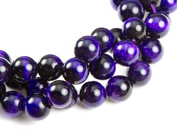 Regal style fills the Dakota Stones 8mm purple tiger eye round beads. Available by the strand, these beads feature a perfectly round shape, making them a classic choice for any design. They feature deep purple color with reflective bands of light dancing on the surface. The 8mm size is perfect for bracelets and necklaces. This gemstone is a variety of quartz that is chatoyant. Mined in North America, Africa and Australia, tiger eye has been used to enhance wealth and vitality.Because gemstones are natural materials, appearances may vary from piece to piece. Each strand includes approximately 47 beads.
