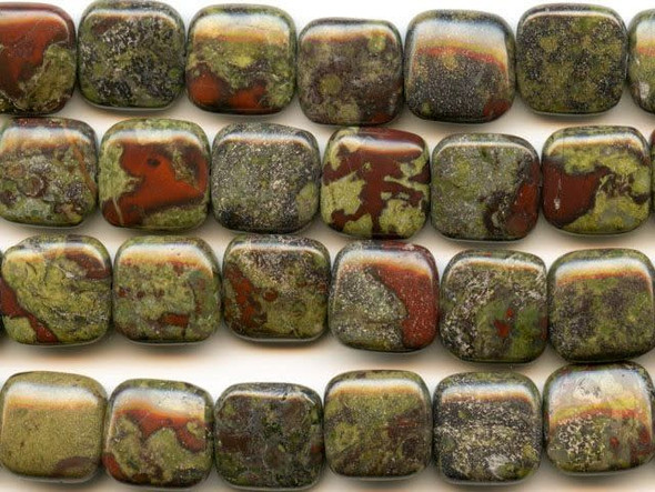 The word jasper is derived from the Greek for "spotted stone" and these dragon blood jasper 12mm square beads from Dakota Stones are full of spotted color. These slightly puffed square-shaped beads feature mottled green flecks of color splashed with deep red tones. The two primary colors contrast and complement each other to form striking jasper. Mined only in western Australia, the local legend surrounding this gemstone says that it is the remains of ancient dragons long dead, the green mottles representing the dragons' scales and the red matrix representing spatters of blood. Dragon blood jasper is part of the quartz family. Metaphysical Properties: Dragon blood jasper enhances courage, strength and vitality.Because gemstones are natural materials, appearances may vary from bead to bead. Each strand includes approximately 16 beads.