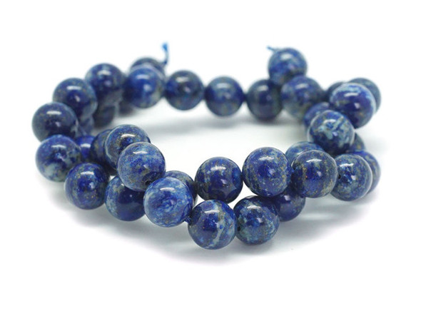 For twinkling touches of beauty in your designs, try these lapis lazuli round beads from Dakota Stones. Available by the strand, these bold beads are spherical in shape and feature glittering golden color sprinkled over a dark blue background. Lapis lazuli is a semi-precious stone that contains primarily lazurite, calcite and pyrite. It was among the first gemstones to be worn as jewelry. Showcase these stunning gemstone beads in a necklace design. Metaphysical Properties: Lapis lazuli is said to enhance insight, intellect and awareness. Because gemstones are natural materials, appearances may vary from bead to bead.