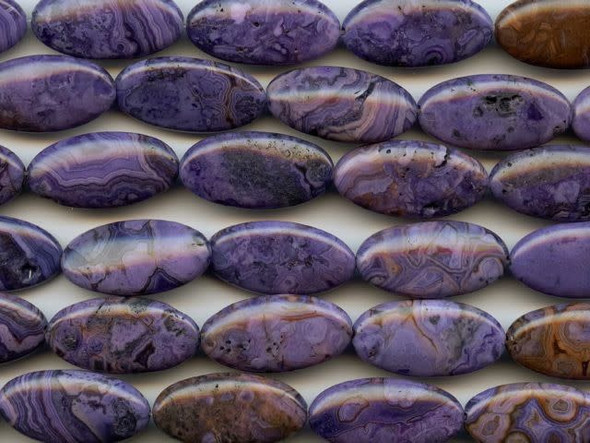 The purple crazy lace agate 15x30mm oval beads are aptly named, because the patterns they display are certainly erratic. These elongated oval-shaped beads would look lovely with turquoise elements. The purple colors are swirled with patterns of burgundy and black. They have a Mohs hardness of 6.5-7. Mexican crazy lace agate is normally an opaque white gemstone with swirling patterns, but these beads are color enhanced to emphasize these beautiful patterns. Color enhancing is common amongst agates to make them fashionably relevant. Metaphysical Properties: Often called the happy stone, crazy lace agate promotes laughter and optimism. Because gemstones are natural materials, appearances may vary from bead to bead. Each strand includes approximately 7 beads.