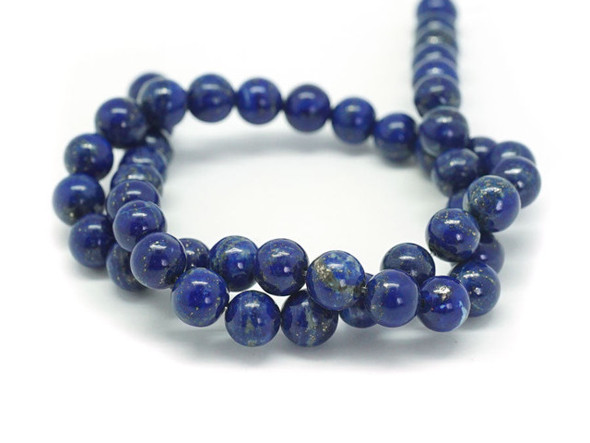 For twinkling touches of beauty in your designs, try these lapis lazuli round beads from Dakota Stones. Available by the strand, these bold beads are spherical in shape and feature glittering golden color sprinkled over a dark blue background. Lapis lazuli is a semi-precious stone that contains primarily lazurite, calcite and pyrite. It was among the first gemstones to be worn as jewelry. Showcase these stunning gemstone beads in a necklace design. Metaphysical Properties: Lapis lazuli is said to enhance insight, intellect and awareness. Because gemstones are natural materials, appearances may vary from bead to bead.
