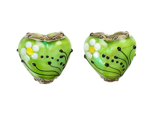 Looking to add a touch of natural beauty to your jewelry collection? Look no further than the Grace Lampwork Spring Green Florals Heart Focal Bead. Crafted from shimmering glass, this bead boasts a soft chartreuse green color that glimmers in the light. The heart-shaped bead is adorned with delicate white and yellow daisies and accented with black swirls and dots, giving it a whimsical, garden-inspired look. Whether you string it onto a head pin or add it to a beaded strand, this handmade bead is sure to add a special touch to all of your DIY creations.