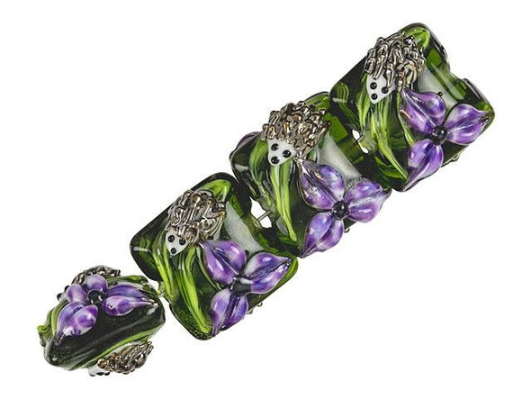 Transform your handmade jewelry into an adorable masterpiece with these Grace Lampwork Iris and Critter Pillow Beads. Made of stunning glass, these beads feature a square shape with a puffed dimension, and are perfect for creating necklaces, bracelets, and earrings. Featuring a charming hedgehog nestled near a purple iris flower delicately crafted on a black background, these beads make your jewelry stand out in the crowd. Enjoy the beauty of nature and bring it to life with these enchanting lampwork glass beads.